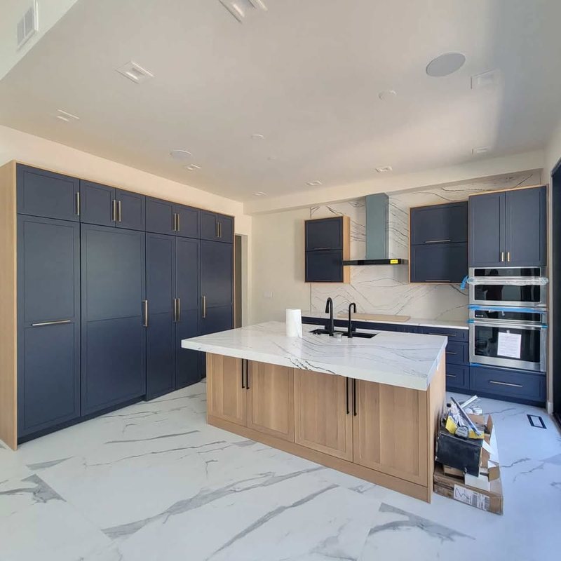Kitchen with navy shaker cabinets, white oak island, marble-look quartz counters and full-height slab backsplash